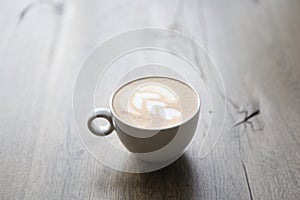 Cappuccino in white glass with wire drawing on milk froth