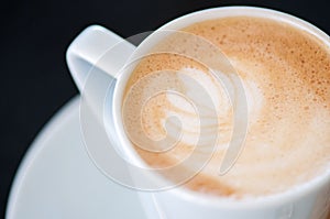 Cappuchino or latte coffe in a white cup on a dark background