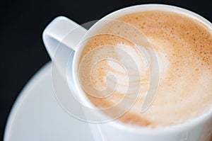 Cappuchino or latte coffe in a white cup on a dark background photo
