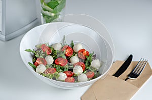 Caprese salad with fresh cherry tomatoes, mini mozzarella, pesto, basil, olive oil and balsamic sauce, with lettuce and arugula