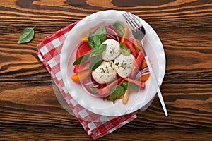 Caprese salad. Italian caprese salad with sliced tomatoes, mozzarella cheese, basil, olive oil in white plate over old wooden braw