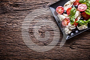 Caprese Salad.Mediterranean salad. Mozzarella cherry tomatoes basil and olive oil on old oak table. Italian cuisine