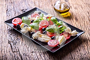 Caprese Salad.Mediterranean salad. Mozzarella cherry tomatoes basil and olive oil on old oak table. Italian cuisine