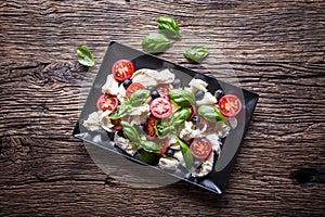 Caprese Salad.Mediterranean salad. Mozzarella cherry tomatoes basil and olive oil on old oak table. Italian cuisine