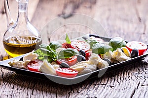 Caprese Salad.Mediterranean salad. Mozzarella cherry tomatoes basil and olive oil on old oak table. Italian cuisine