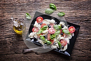 Caprese Salad.Mediterranean salad. Mozzarella cherry tomatoes basil and olive oil on old oak table. Italian cuisine