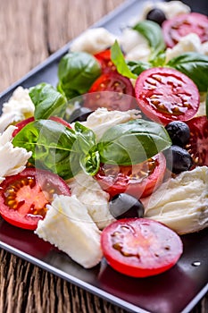 Caprese Salad.Mediterranean salad. Mozzarella cherry tomatoes basil and olive oil on old oak table. Italian cuisine
