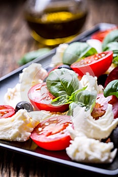 Caprese Salad.Mediterranean salad. Mozzarella cherry tomatoes basil and olive oil on old oak table. Italian cuisine