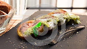 Caprese salad with mozzarella, black tomatoes and pesto on black stone plate