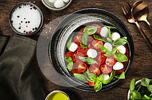 Caprese salad with ripe red tomatoes and mozzarella cheese with fresh green basil leaves. Italian food. Top view, wooden