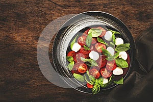 Caprese salad with ripe red tomatoes and mozzarella cheese with fresh green basil leaves. Italian food. Top view, wooden