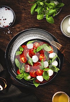 Caprese salad with ripe red tomatoes and mozzarella cheese with fresh green basil leaves. Italian food. Top view, wooden