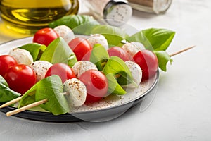 Caprese salad - skewer with tomato, mozzarella and basil, italian food and healthy vegetarian diet concept on a light background