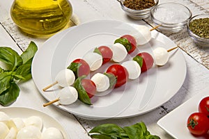 Caprese salad on sticks on an white wooden table. Selected focus.