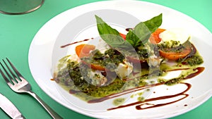 Caprese salad with tomatoes, mozzarella and basil. Red and orange tomatoes with white cheese and sauce. Portion of food