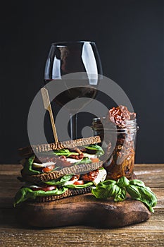 Caprese sandwich, glass of wine and dried tomatoes in jar