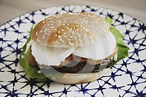 Caprese style hamburger topped with slices of fresh mozzarella cheese, tomato, basil leaves, and lettuce on toasted brioche bun on