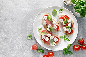 Caprese toasts with mini mozzarella cheese, cherry tomato and basil, top view