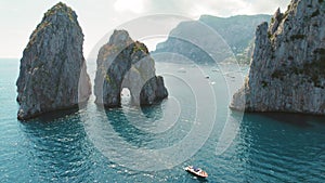 Capri Island with iconic sea stacks Faraglioni rise from the Tyrrhenian Sea. Leisure yachts and boats in the idyllic