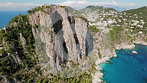 Capri Island with rocky natural arch formations. High cliffs and deep blue sea in Italy. Summer popular tourist