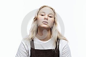 A capricious teenage girl. A cute blonde with freckles in a white T-shirt and brown overalls with an arrogant face. White