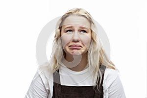 A capricious teenage girl. A cute blonde with freckles in a white T-shirt and brown overalls. White background. Close-up.