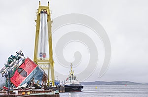 Capsized ship vessel and rescue lift crane at port dock for repair of shipwreck