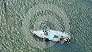 Capsized sunken sailing boat left forsaken on shallow bay waters after hurricane Ian in Manasota, Florida