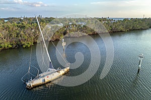 Capsized sunken sailing boat left forsaken on shallow bay waters after hurricane Ian in Manasota, Florida