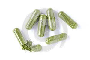 Closeup green herbal powder medicine capsules pills isolated on white background. photo