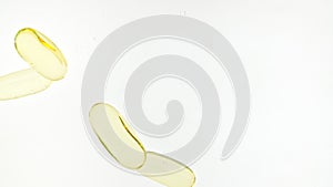 Capsule pills, Omega 3 gold oil capsules. Macro shot of Pills falling down in water and air bubbles on white background