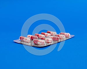 Capsule tablets in a package on a blue background.