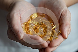 Capsules of cod-liver oil fall into palms of mature woman