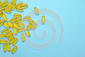 Capsules of fish fat oil, omega 3, vitamin e on the blue background with copy space. Healthcare, vitamins, supplements daily