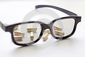 Capsules with glasses on light background. Pharmacy and medicine for eyes concept