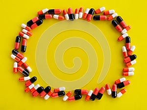 Capsules of medicine are located around the perimeter on a yellow background with an empty place for text in the center, top view