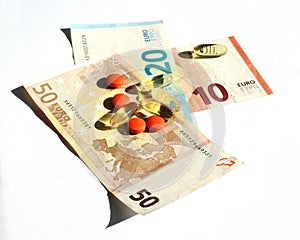 Capsules of omega 3 and orange tablets against pain laid on Euro banknotes. Pharmaceutical business