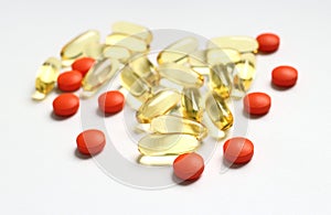 Capsules of omega 3 and orange tablets against pain on white background