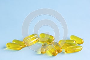 Capsules omega3, pills fish oil, cod-liver fat or flaxseed linseed oil on light blue background