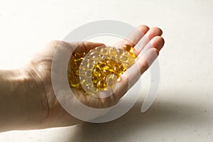 Capsules are in palm, hand food supplement oil filled capsules vitamin A, vitamin D3, fish oil, omega 3, 6, 9, evening primrose,
