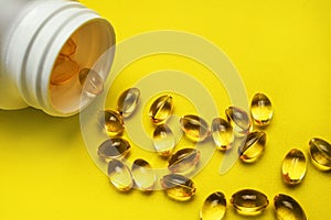 Capsules pill with vitamin D poured out of white plastic packaging on yellow background. Fish oil, Omega, Omega-3, dietary