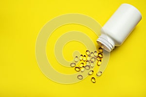 Capsules pill with vitamin D poured out of white plastic packaging on yellow background. Fish oil, Omega, Omega-3, dietary