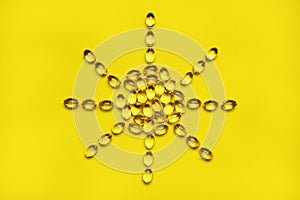 Capsules pill vitamin D sun shaped on yellow background close-up. Fish oil, Omega, Omega-3, dietary supplement, sunshine vitamin. photo