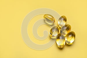 Capsules pill with vitamin D on yellow background close-up. Fish oil, Omega, Omega-3, dietary supplement, sunshine vitamin.