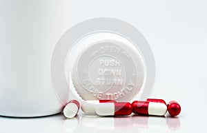 Capsules pills on white background and plastic bottle with blank label and copy space. Childproof packaging. Child resistant pill