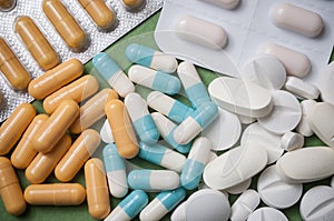 Capsules, pils and drug tablets on green background