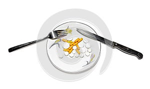 Capsules and tablets on a saucer with a knife and fork