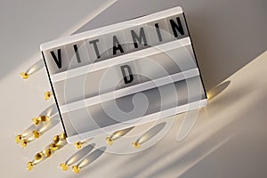 Capsules with vitamin D on the white table with natural sunlight.