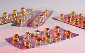 Capsules with yellow medicine on light red background