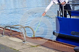 Captain or helmsman attaches the boat to the harbor quay with a rope, copy space